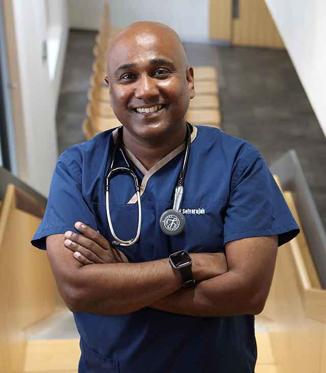 Portrait image of Dr Selvaseelan-Selvarajah wearing blue medical gown with stethoscope around his neck 